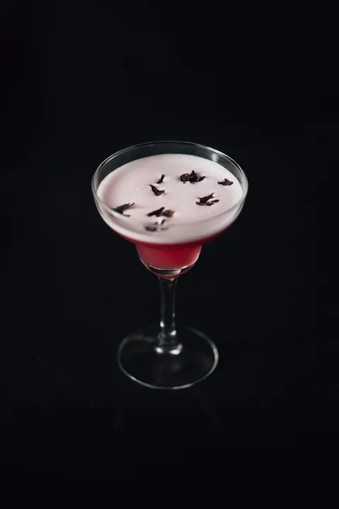 Un cocktail rouge sous une mousse blanche, servi en coupe