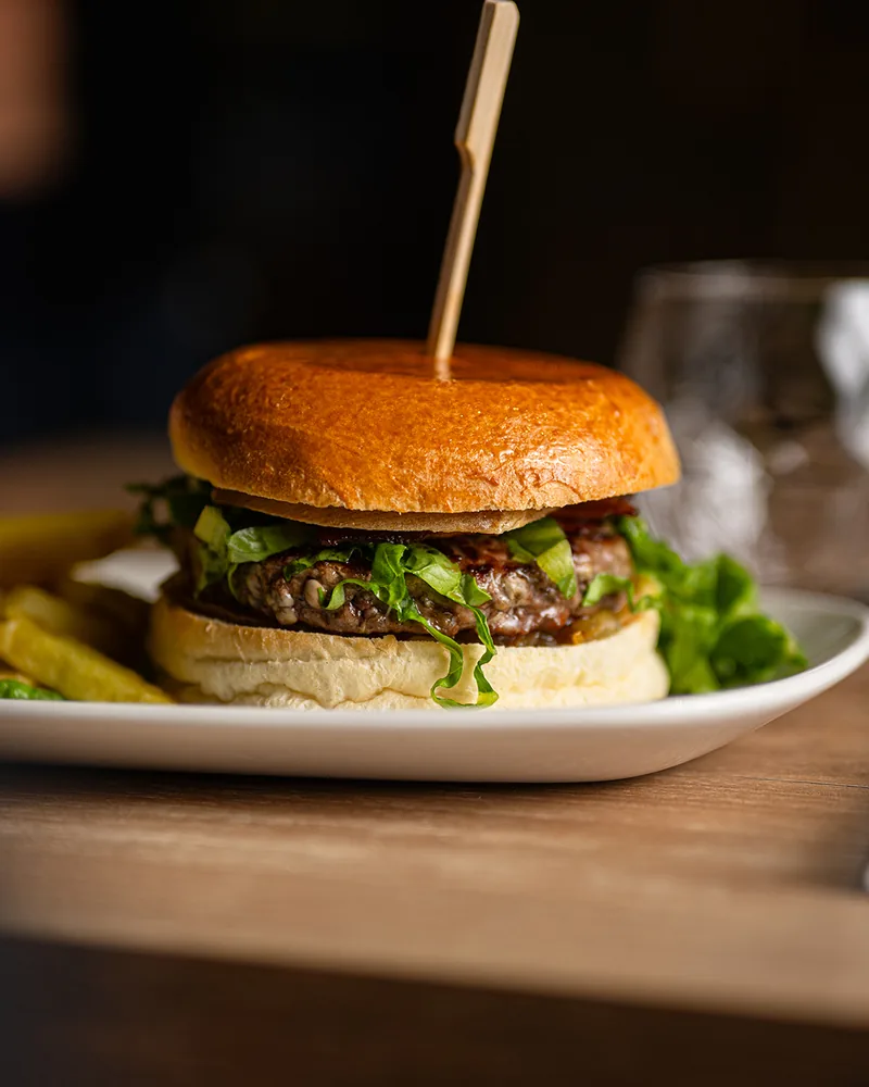 Le burger montagnard : bun brioché, steak charolais, raclette et lard grillé