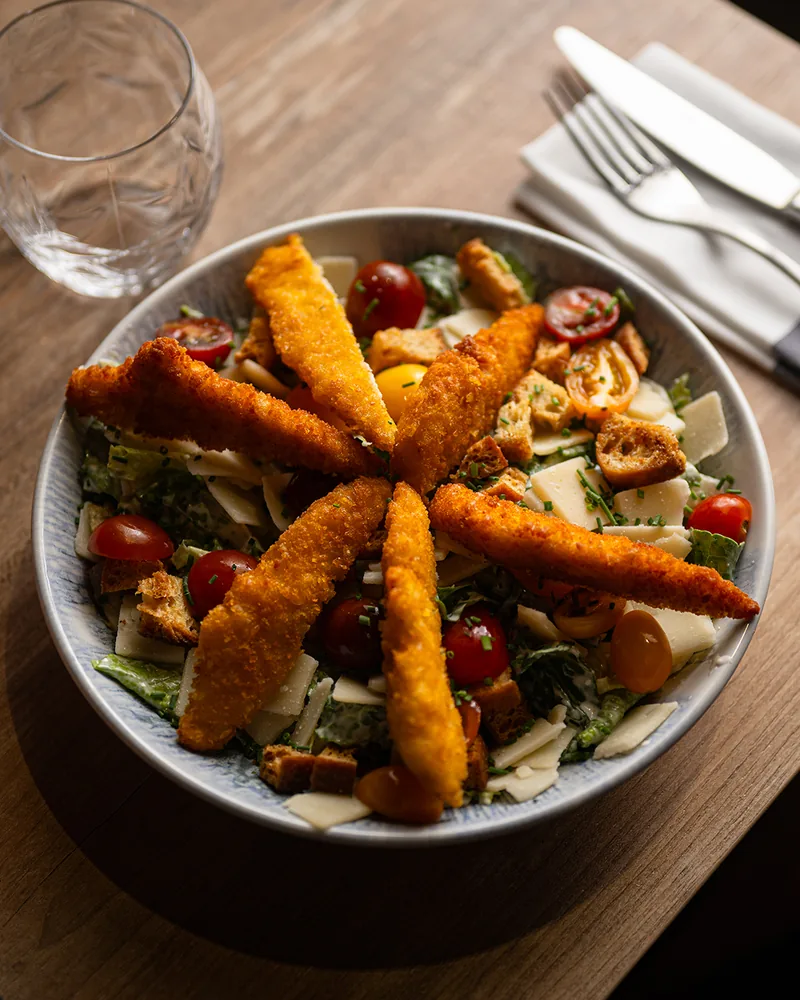 La salade Caesar : romaine, volaille panée, croûtons, tomates cerises et parmesan