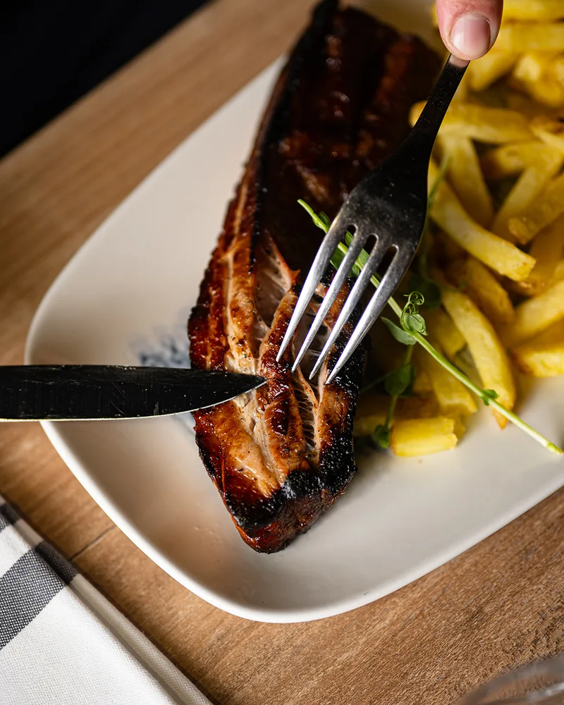 La poitrine de porc caramélisée au feu de bois, avec des frites