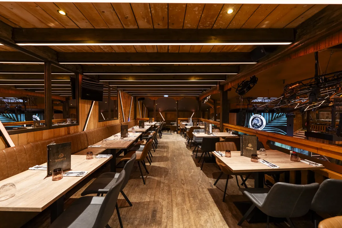 La salle du restaurant, ses tables en bois sous la charpente