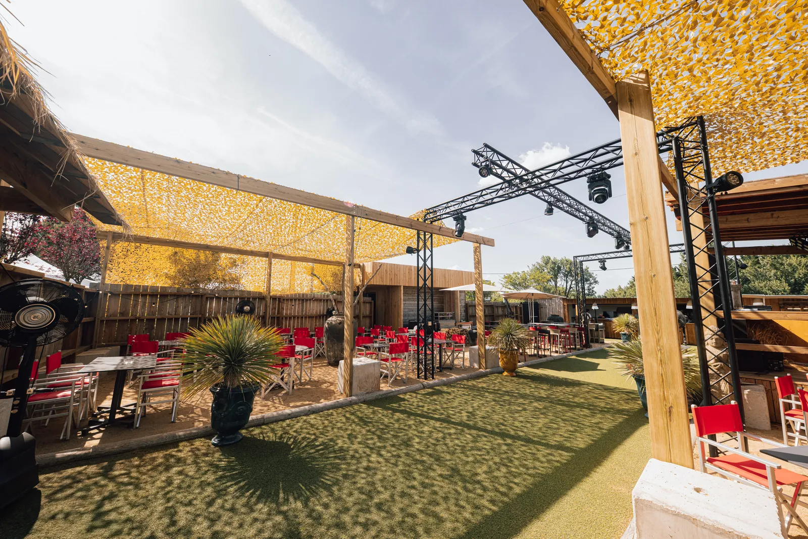 La terrasse en plein air, ses tables et ses grandes lampes