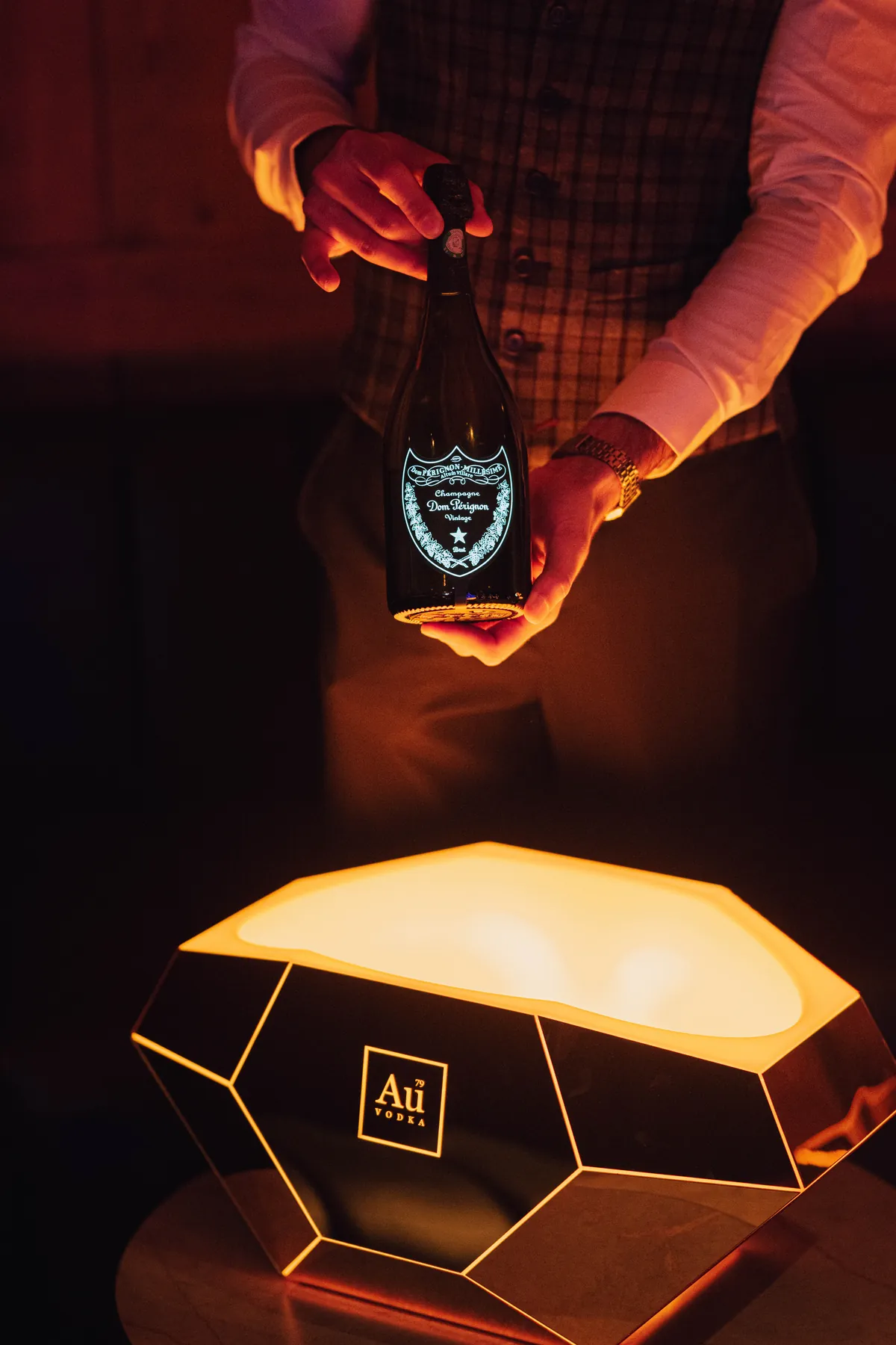 Une bouteille de Dom Pérignon présentée au-dessus d’un seau Au Vodka lumineux